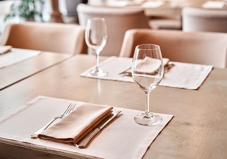 Wine glasses in the foreground. The chairs and table for guests, served with cutlery and crockery.